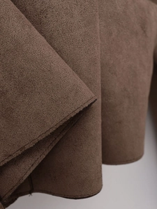Detailed close-up of dark brown faux suede fabric and high-quality stitching on jacket cuff