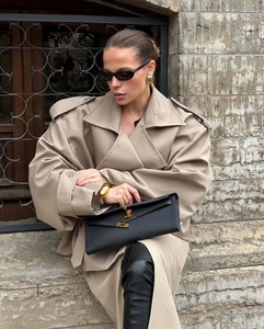 Close-up of black litchi leather bag with gold clasp and autumn trench coat styling