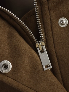 Détail macro de la fermeture éclair argentée et boutons étoilés sur veste en daim marron