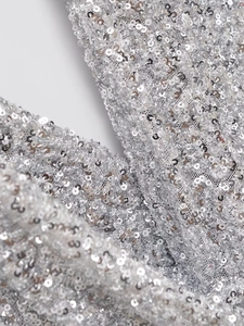 Vue macro de paillettes argentées scintillantes sur tissu en maille pour vêtements de fête