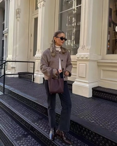 Winter brown wool jacket paired with white turtleneck and black jeans on city steps