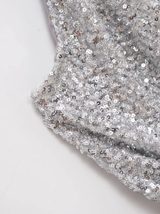 Gros plan de paillettes argentées sur tissu gris montrant une texture réfléchissante
