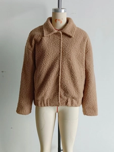 Detail of warm brown faux shearling jacket showing plush texture and lapel collar