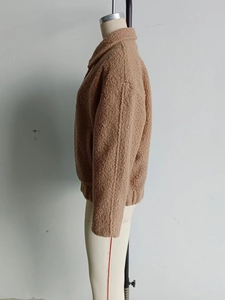 Detail view of the tan fleece jacket showing thick textured material and elastic cuffs