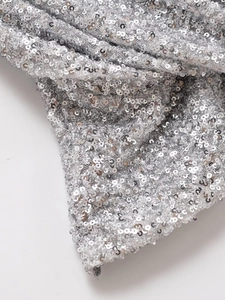 Gros plan de paillettes argentées scintillantes sur un haut dos nu à col licou chic
