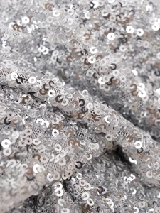 Gros plan de sequins argentés sur tissu mesh montrant la texture détaillée et l'éclat