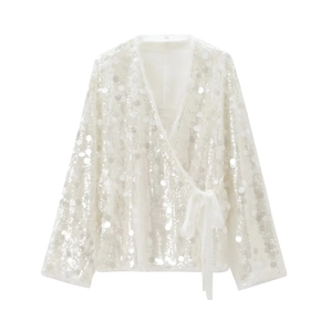 Macro detail of shimmering white sequins and chiffon tie-waist on a wrap jacket