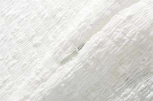 Dettaglio macro del tessuto arricciato bianco con cerniera invisibile a scomparsa