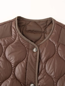 Détail de l'encolure ronde et des boutons sur la veste matelassée marron foncé avec coutures
