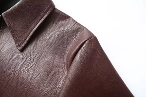 Dettaglio del colletto e cucitura della spalla di una giacca in pelle PU bordeaux