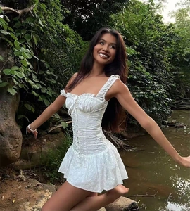 Dettaglio mini abito in cotone bianco con allacciatura a corsetto e ricami floreali