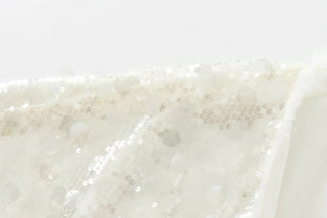 Macro shot of elegant white sequins and feather details on a chic kimono-style sequined jacket