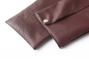 Dettaglio manica in pelle PU bordeaux scuro con bottone automatico in metallo e cuciture