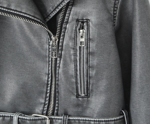 Close-up of vintage faux leather jacket showing metallic zipper and washed texture detail
