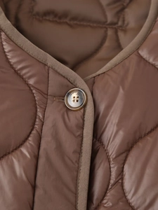 Détail macro d'une veste matelassée marron avec passepoil raffiné et fermeture à bouton