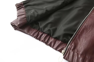 Dettaglio della giacca in PU bordeaux con texture litchi, orlo elastico e zip in metallo