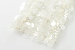 Close-up of white sequin fabric with fringe detail on a stylish kimono jacket for women