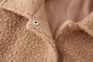 Detail of camel faux shearling jacket showing soft curly texture and silver snap button