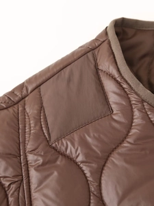 Gros plan sur la veste matelassée marron montrant le tissu ripstop et les surpiqûres