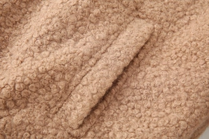 Detail shot of the plush teddy fleece texture and pocket stitching on the brown jacket