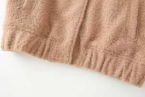 Detail of khaki faux shearling jacket showing ribbed hem and textured teddy fleece fabric