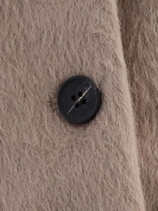 Macro shot of black four-eye button on fluffy wool-like beige winter jacket fabric