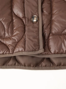 Détail d'une veste matelassée marron foncé avec motif oignon et fermeture à bouton rond