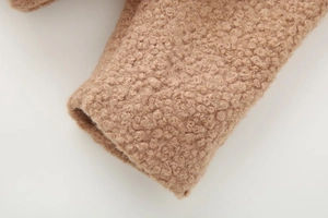 Detailed macro view of camel faux shearling sleeve cuff texture and soft curly fabric