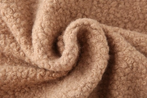 Macro shot of thick brown sherpa fleece fabric texture with soft curly wool detail
