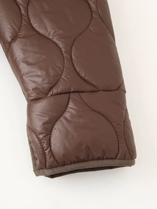 Vue détaillée de la manche matelassée ondulée sur veste marron avec bordure contrastée