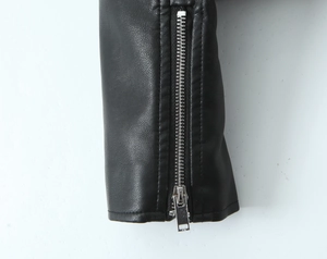 Gros plan sur le poignet d'une veste en similicuir noir avec une fermeture éclair en métal