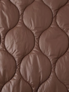 Gros plan du matelassage oignon sur tissu nylon ripstop marron avec coutures précises
