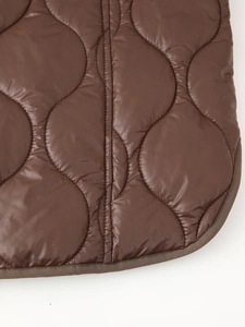Détail de la veste matelassée marron avec motif vagues et finitions de bordure soignées