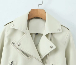 Détail du revers et du col d'un blouson biker en similicuir crème avec étiquette XS