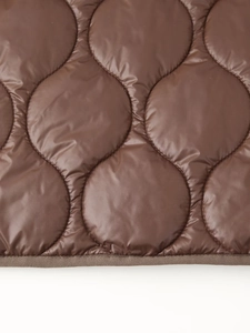 Détail macro du tissu matelassé ondulé avec coutures denses et bordure en ruban brun