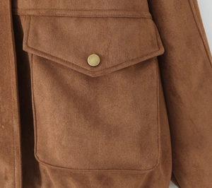 Close-up of brown suede jacket showing large flap pocket and brass button detail