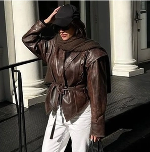 Outdoor-Streetstyle-Foto einer Vintage-Kunstlederjacke in Dunkelbraun mit Gürtel