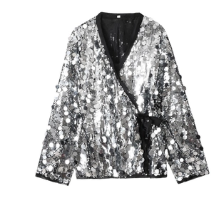 Detail of silver sequin wrap top featuring black satin bow and shimmering texture