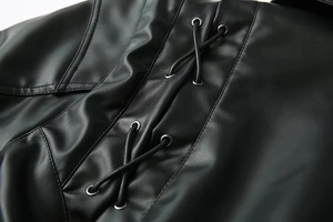 Detailansicht der schwarzen Kunstlederjacke mit Punk-Stil Schnürung und Silberösen im Makro