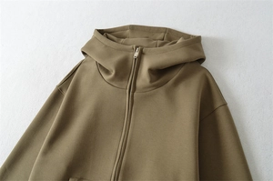 Détail du sweat à capuche zippé vert olive montrant le col haut et la texture du tissu