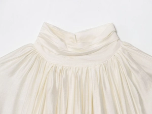 Detailed close-up of high-neck gathered collar on elegant off-white long sleeve blouse
