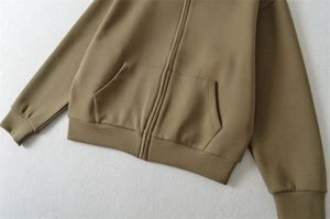 Détail d'un sweat à capuche kaki foncé avec fermeture éclair et poignets côtelés
