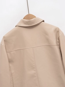Detailed macro view of beige faux leather jacket featuring premium stitching and shirt collar