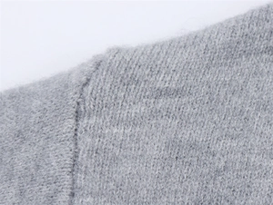 Nahaufnahme der Schulternaht eines grauen Strickpullovers mit weicher Wollstruktur