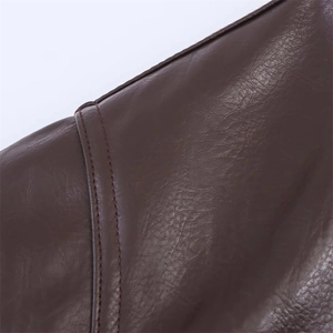 Détail d'une veste en similicuir marron foncé avec texture lychee et coutures
