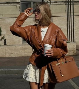 Detail einer karamellbraunen Kunstlederjacke mit Gürtel und Schnürung an den Ärmeln