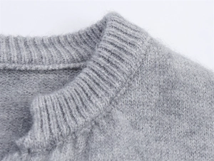 Detailansicht eines grauen Strickpullovers mit weicher Textur und geripptem Halsausschnitt