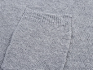 Detaillierte Nahaufnahme der gerippten Tasche an einem grauen Strickpullover