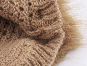 Macro detail of camel knit fabric featuring hollow-out pattern and plush fur trim texture