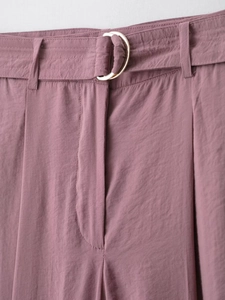 Dettaglio dei pantaloni a vita alta con cintura in tessuto e fibbia dorata a D